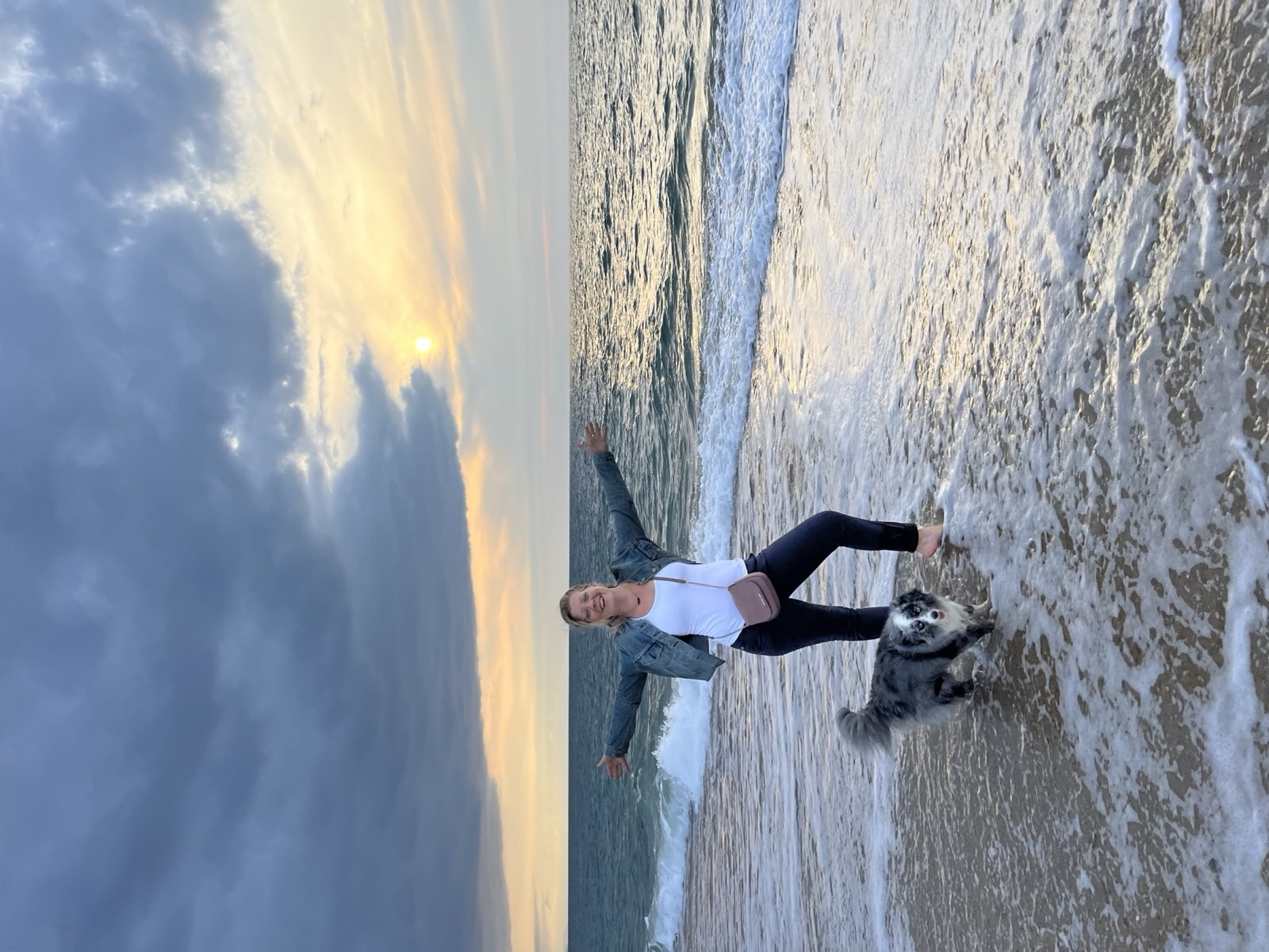 Mary Picart les bras ouverts sur une plage du Pays Basque, sa chienne Pyla à ses pieds